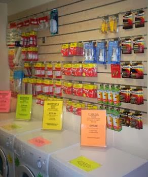 A wall of appliance spares and accessories in the shop, above washing machines with bright price cards